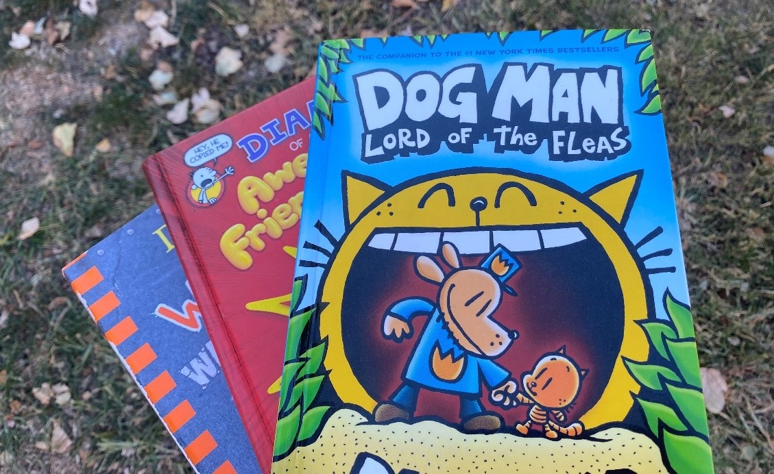 Three copies of Dog Man books fanned out on the ground.